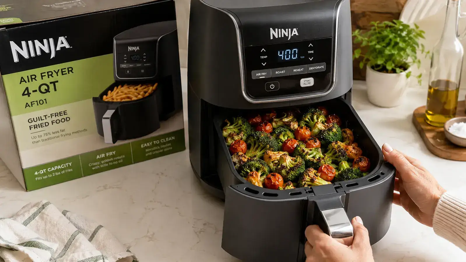 Ninja air fryer basket open with crispy roasted vegetables inside, sitting on a small kitchen counter