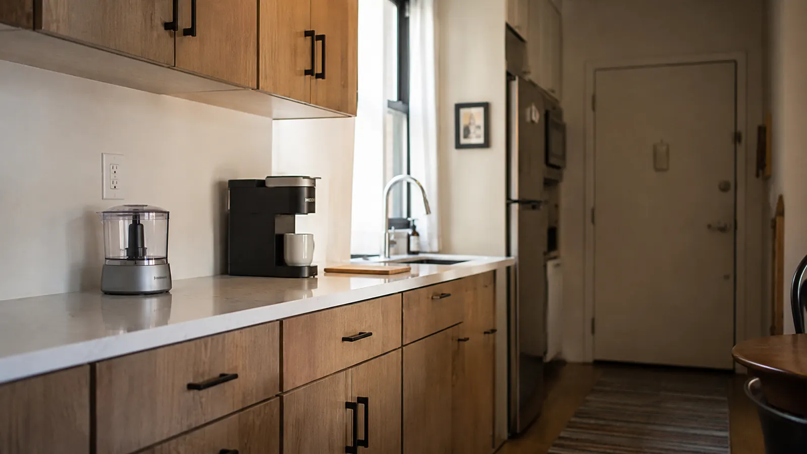 Apartment kitchen counter with only a mini food chopper, coffee maker, and small cutting board showing available space