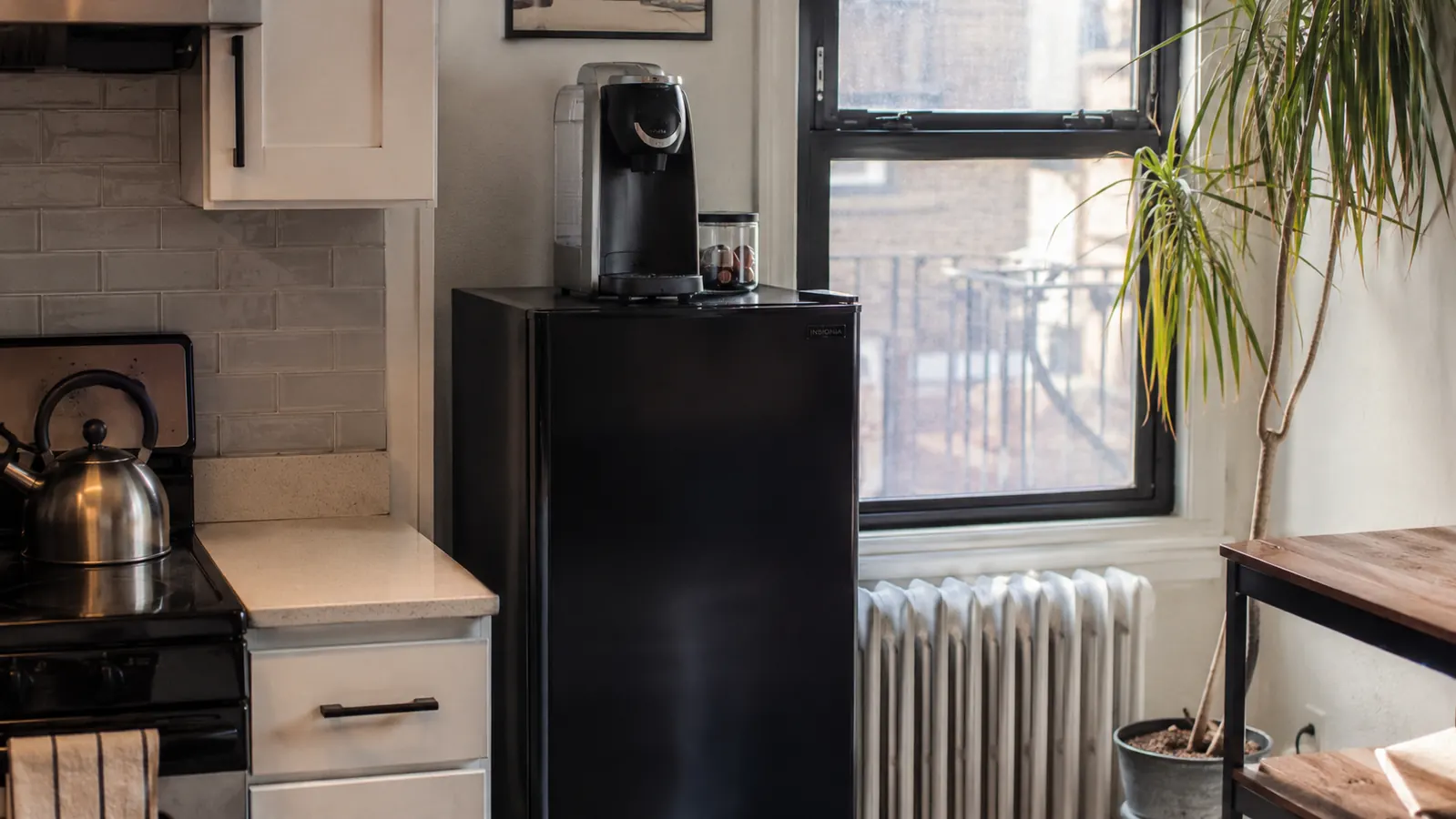Keurig K-Mini stored on top of a small refrigerator next to a cabinet in a tight apartment kitchen